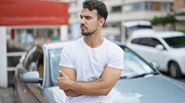 Sokakta kolları çaprazlanmış bir şekilde arabada oturan İspanyol genç adam.