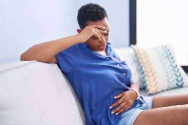 Afrika kökenli Amerikalı kadın evde baş ve mide ağrısı çekiyor.