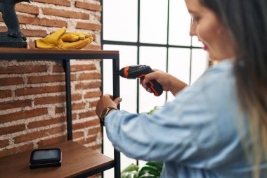 Young beautiful plus size woman smiling confident repairing shelving at new home