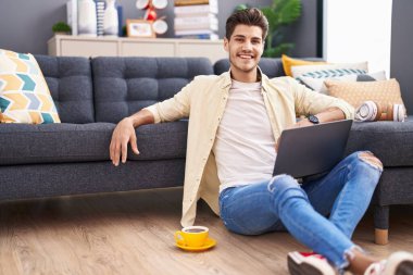 Genç İspanyol adam evde dizüstü bilgisayar kullanıyor.