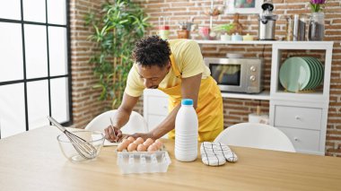 Afro-Amerikalı aşçı yemek odasında deftere yazı yazıyor.