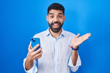 Sakallı İspanyol bir adam akıllı telefondan mesaj yazıyor. Avuç içleri açık, fotokopi alanını gösteriyor. Gülümseyen mutlu bir gülümseme. 