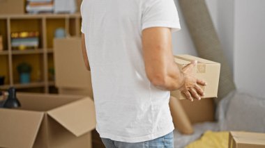 Genç İspanyol adam yeni evinde paket tutuyor.