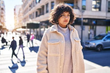 Young beautiful hispanic woman looking to the side with serious expression at street