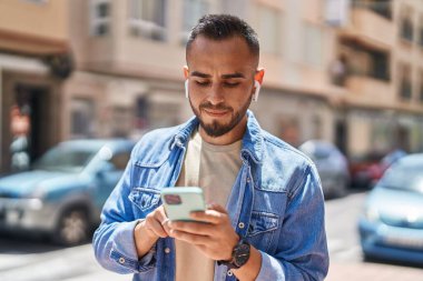 Sokakta müzik dinlerken kendinden emin gülümseyen İspanyol genç adam.