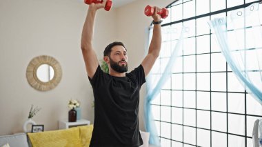 Genç İspanyol adam evde dambıl eğitimi alıyor.