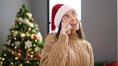 Genç, güzel, İspanyol bir kadın akıllı telefondan Noel 'i evde kutluyor.