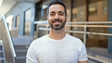 Sokakta kendinden emin gülümseyen İspanyol genç adam.