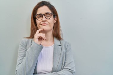 Gri arka planda duran esmer kadın kameraya kolları çapraz ve çenesi açık gülümsüyor. Olumlu düşünmek. 