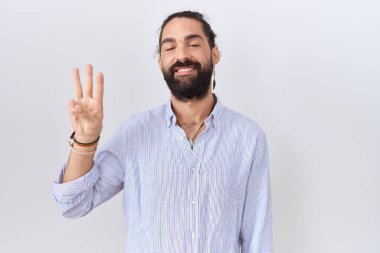 Hispanic man with beard wearing casual shirt showing and pointing up with fingers number three while smiling confident and happy. 