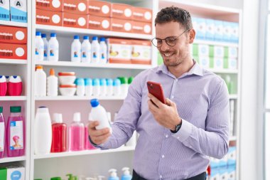 Young hispanic man customer make photo by smartphone to medicine bottle at pharmacy