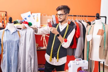 Genç İspanyol terzi atölyeden gömleğe akıllı telefondan fotoğraf çekiyor.