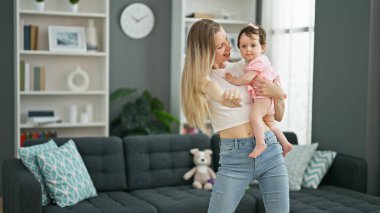 Anne ve kızı evde dans ederken birbirlerine sarılıyorlar.