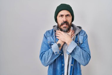 Yün şapka takan İspanyol dövmeli genç adam bağırıyor ve boğuluyor çünkü boğularak can yakıyor. Sağlık problemi. Boğulma ve intihar konsepti. 
