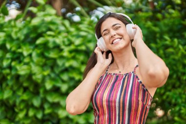 Genç, güzel İspanyol kadın parkta müzik dinliyor ve dans ediyor.