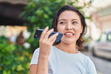 Genç İspanyol kadın gülümsüyor. Kendine güveniyor. Akıllı telefondan konuşuyor.