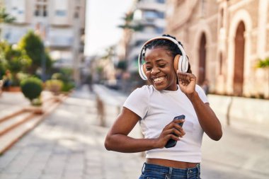 Sokak ortasında müzik dinleyen ve dans eden Afrikalı Amerikalı bir kadın.