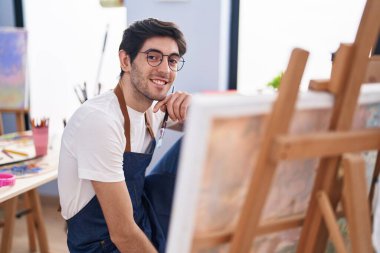 Genç İspanyol ressam gülümsüyor. Sanat stüdyosuna özgüvenli bakıyor.