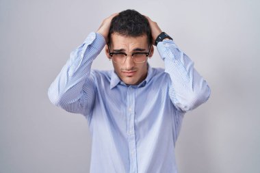 İş kıyafetleri ve gözlük takan yakışıklı İspanyol adam baş ağrısı ve stres altında çünkü ağrı ve migren. Eller başının üstünde.. 