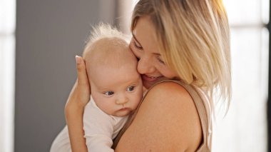 Mother and daughter hugging each other standing at home