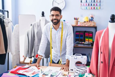 Young arab man tailor smiling confident standing at tailor shop