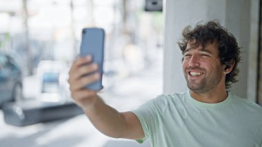 Young hispanic man smiling confident having video call at street