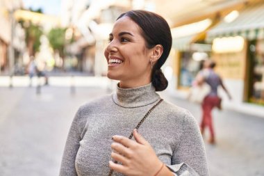 Young beautiful hispanic woman smiling confident looking to the side at street