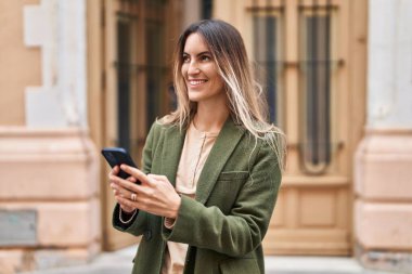 Sokakta akıllı telefon kullanan kendine güvenen genç bir kadın.