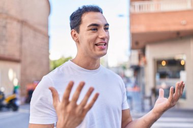 Genç İspanyol adam gülümsüyor Sokakta kendinden emin konuşuyor