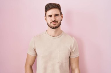 Sakallı İspanyol bir adam pembe arka planda durup komik suratlı yanakları şişiriyor. Havayla şişmiş ağız, çılgın bir ifade.. 