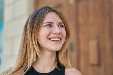 Young blonde woman smiling confident looking to the side at street