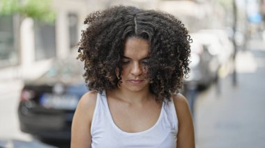 Genç, güzel, İspanyol bir kadın ciddi bir ifadeyle sokağa bakıyor.