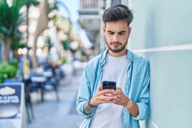 Genç İspanyol adam akıllı telefon kullanıyor. Sokakta ciddi bir ifadesi var.