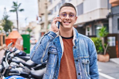 Genç İspanyol adam gülümsüyor. Kendine güveniyor. Sokakta akıllı telefondan konuşuyor.