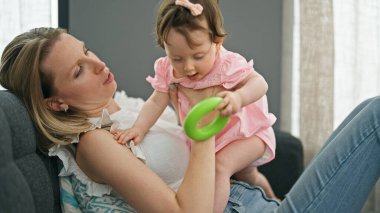 Mother and daughter hugging each other sitting on sofa at home