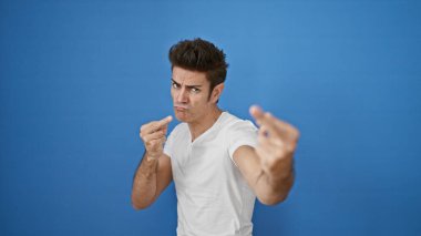 Genç İspanyol adam izole edilmiş mavi arka planda orta parmak hareketi yapıyor.