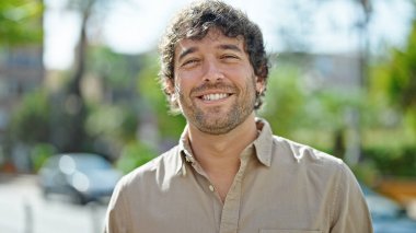 Parkta kendinden emin gülümseyen İspanyol genç adam.