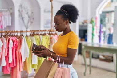 African american woman customer holding shopping bags and wallet at clothing store