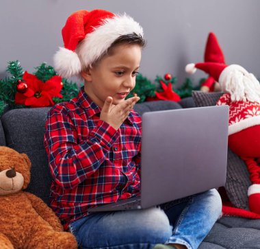 Sevimli İspanyol çocuk evdeki Noel süslemeleriyle birlikte koltukta oturuyor.
