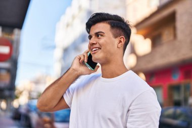 Genç İspanyol adam gülümsüyor. Kendine güveniyor. Sokakta akıllı telefondan konuşuyor.