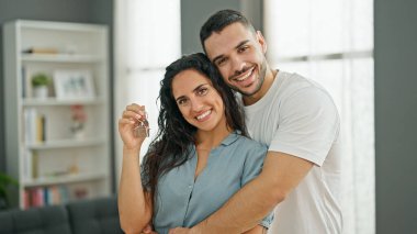 Kadın ve erkek ev anahtarlarını tutarak birbirlerine sarılıyorlar.