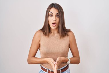 Young hispanic woman standing over white background afraid and shocked with surprise and amazed expression, fear and excited face. 