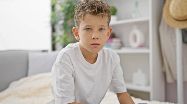 Sevimli sarışın çocuk rahat bir oturma odasında dinleniyor, ciddi bir yüz ifadesiyle evde kanepede otururken konsantre oluyor.