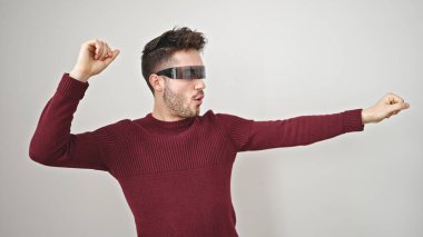 Sanal gerçeklik gözlüğü kullanan genç İspanyol adam izole beyaz arka planda dans ediyor.
