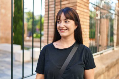 Young beautiful hispanic woman smiling confident looking to the side at street