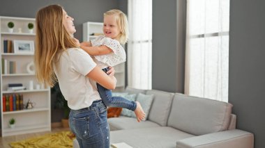 Neşeli anne güler yüzlü kızını kollarına alır, rahat evlerinde dimdik durur.