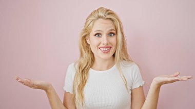 Soyutlanmış pembe arka planda hiçbir şeyden habersiz genç sarışın kadın.