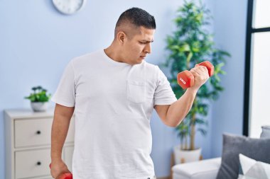 Young latin man using dumbbells training at home