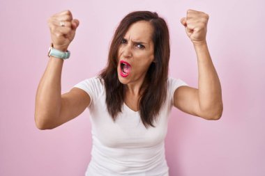 Orta yaşlı esmer kadın, öfkeyle bağırırken kızgın ve kızgın yumruklar sallıyor. öfke ve agresif konsept. 