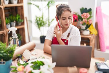 Çiçekçide bilgisayarla konuşan sarışın bir çiçekçi.